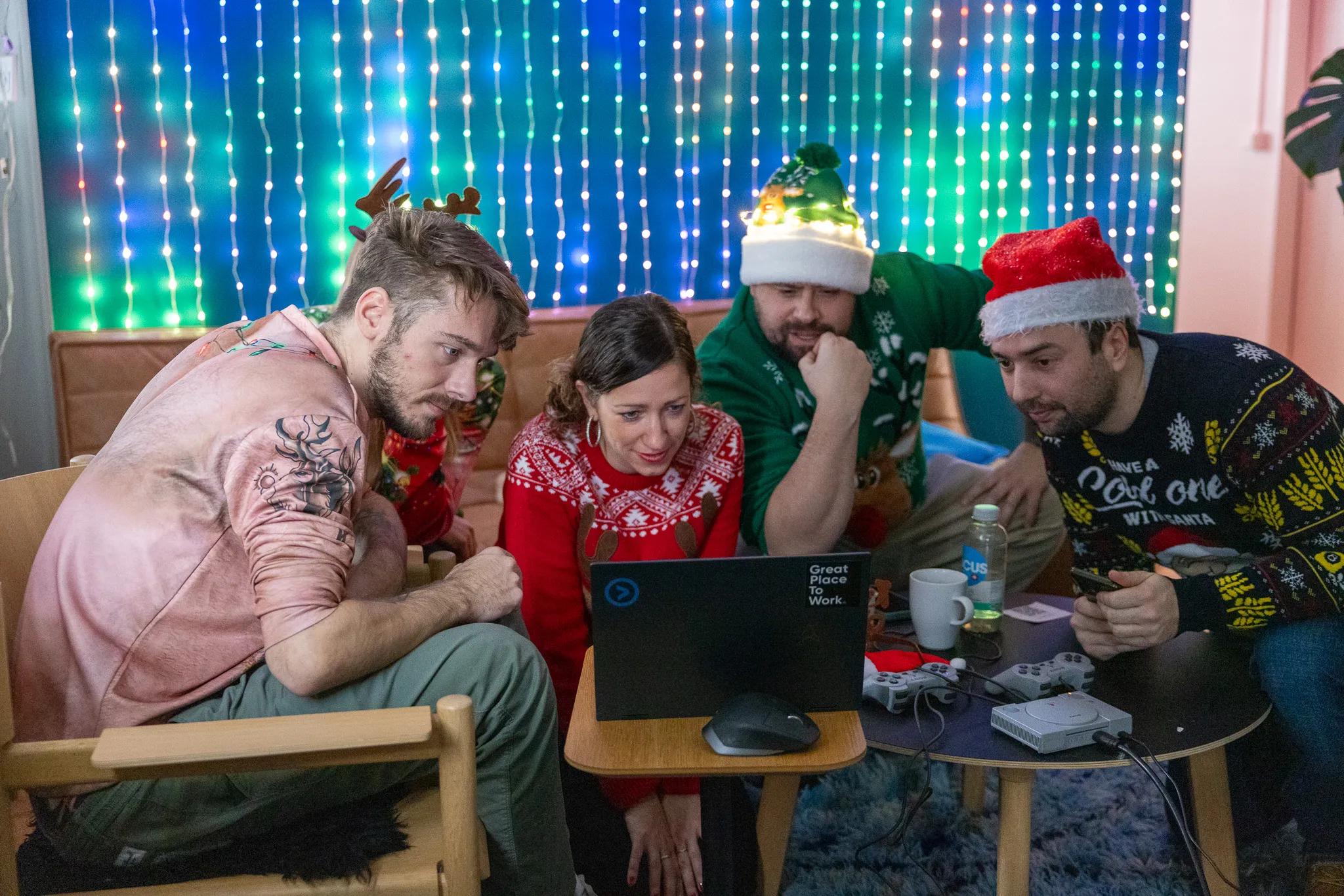 Weihnachtlich gekleidete Mitarbeitende schauen zusammen auf einen Laptop-Bildschirm