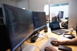 Arbeitsplatz eines Software-Entwicklers mit Codezeilen auf den Bildschirmen.